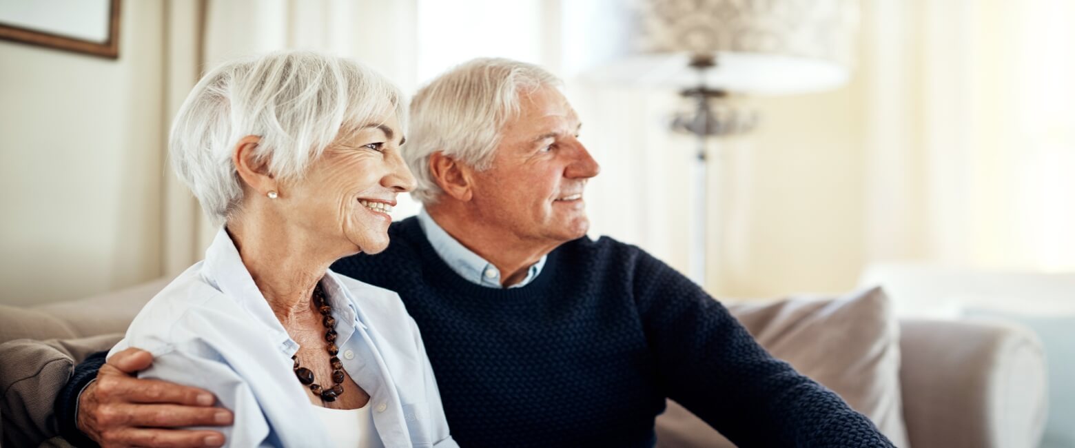 senior couple smiling while sitting together on a couch