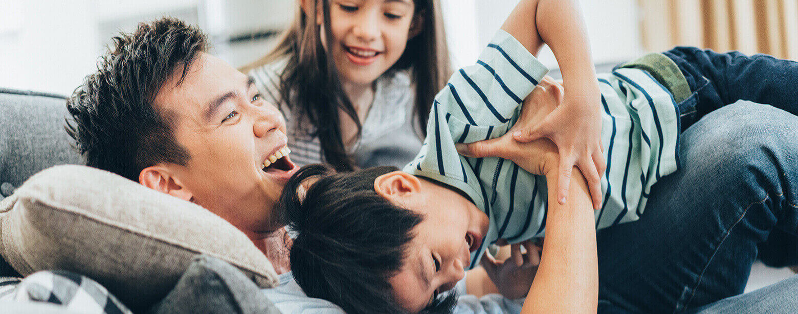 father playing with kids on couch