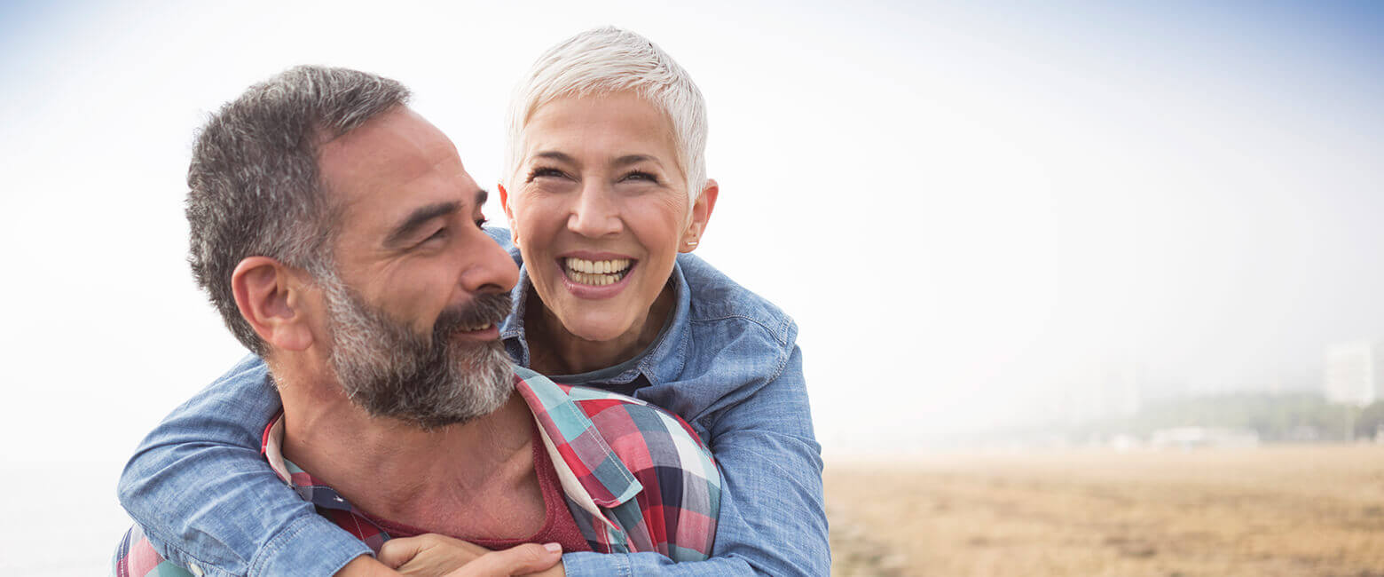 older couple smiling and hugging in field