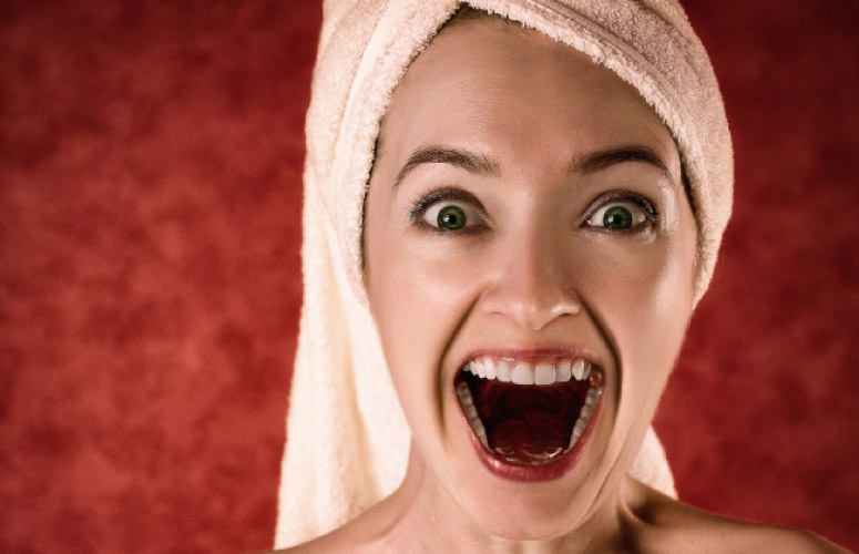 woman with a towel on her head and open mouth after using mouthwash