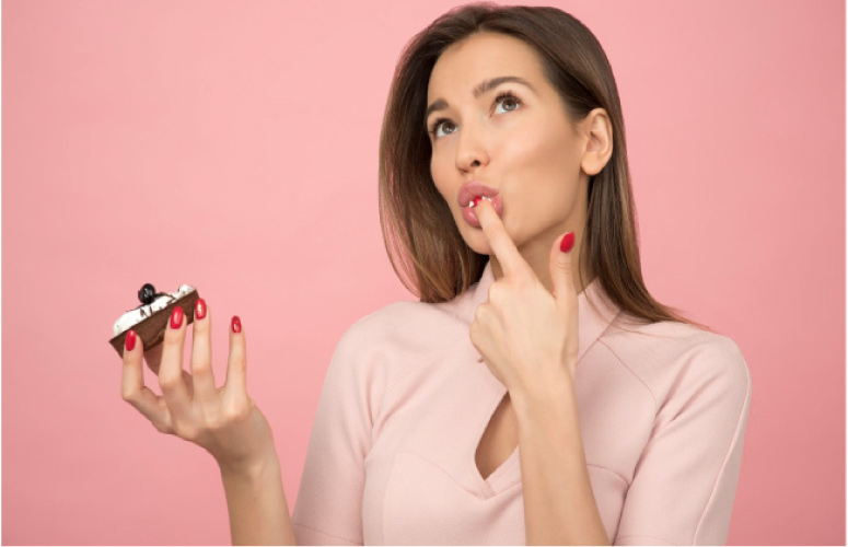 woman holding a donut licking frosting off her finger