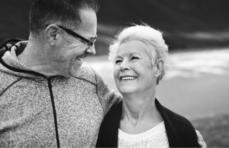 elderly couple hugging and smiling at each other