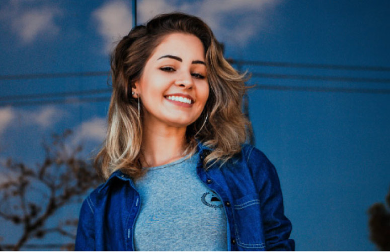 girl wearing a denim jacket smiles showing off her dental veneers