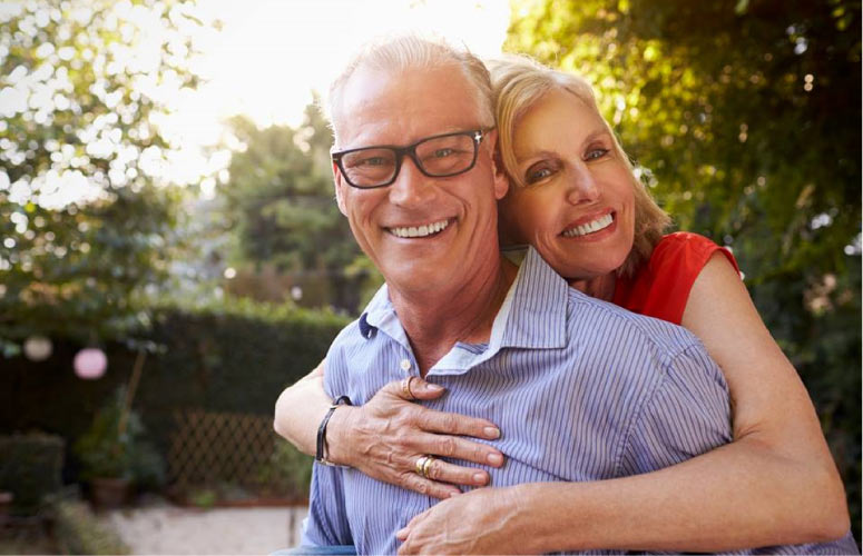 senior couple hugs and smiles after learning about dental implants