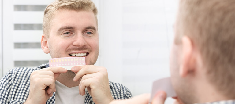 Man whitening teeth against a scale