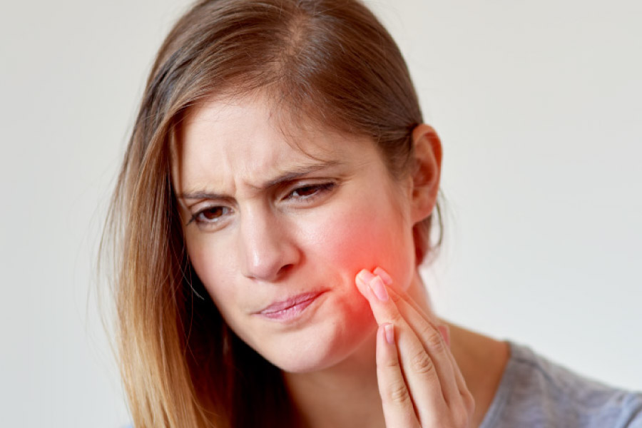 Young woman holding her cheek because of a painful tooth.