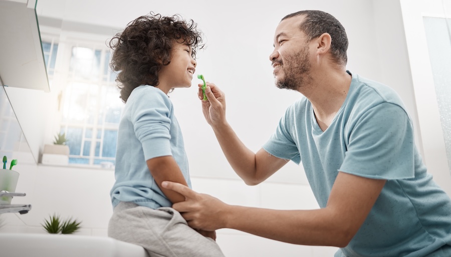 fathering helping child to brush and floss
